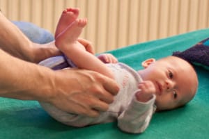 Craniosacrale Therapie bei Kindern: sanfte Behandlung der Beine eines Säuglings